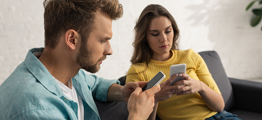 Paar sitzt jeder mit Handy auf dem Sofa