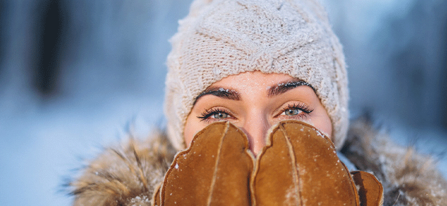 Frau geht im Schnee spazieren und lächelt trotz Winterdepression